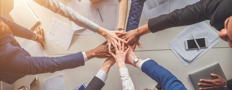 team of men and women with their hands in the middle